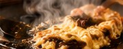 湯気の立つ鉄板の上のお好み焼き